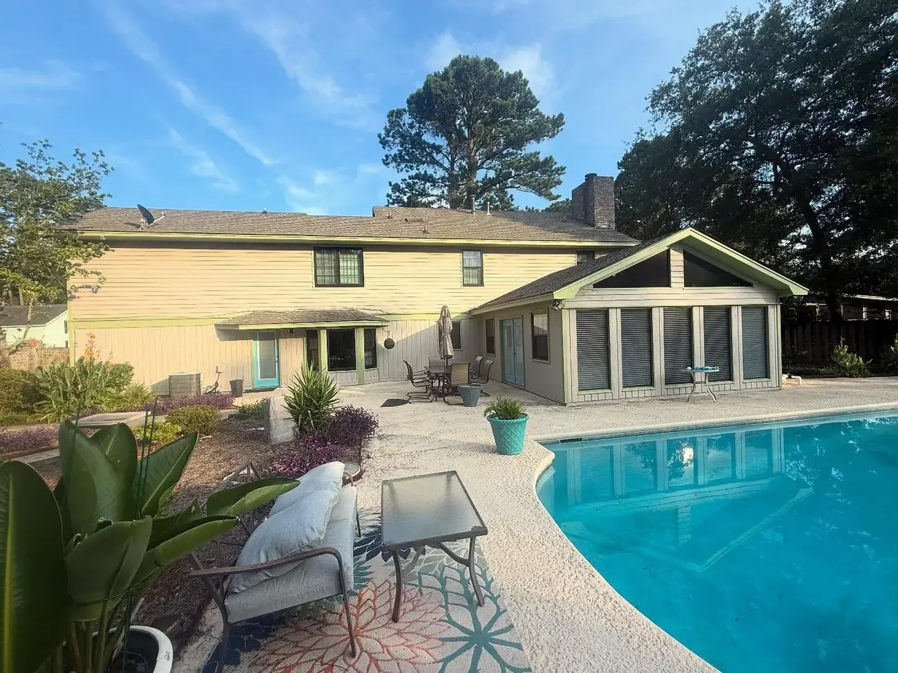 Rear exterior of a two-story home freshly painted in warm cream with sage green accents
