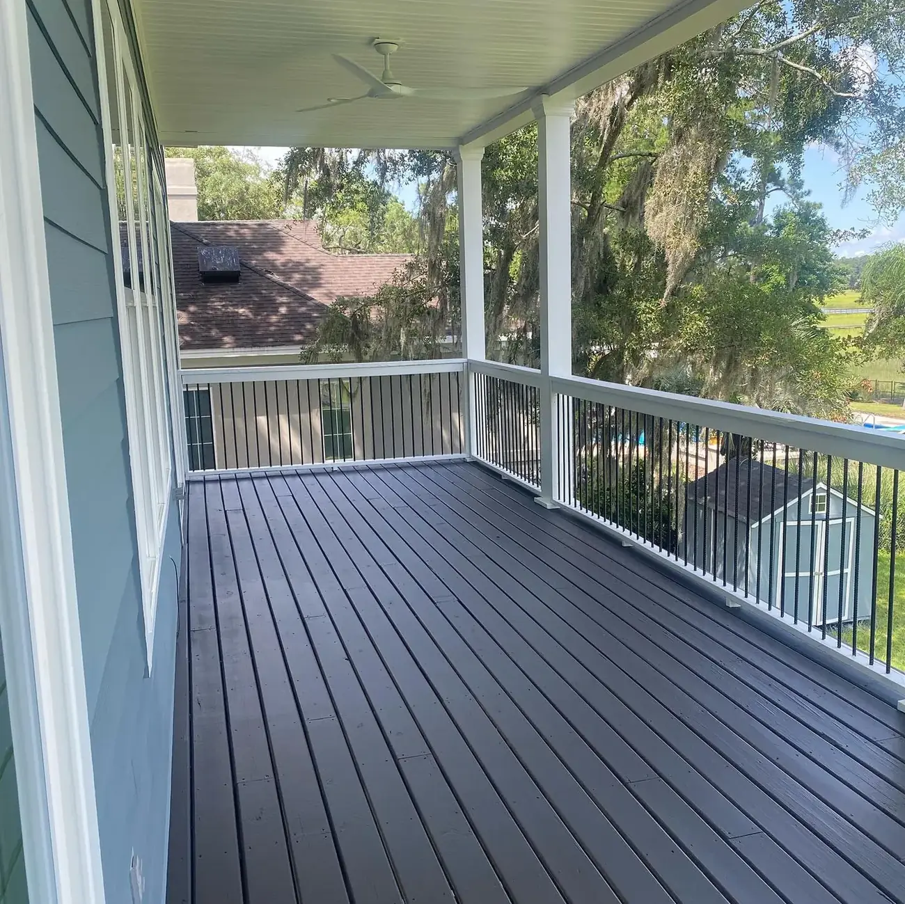 Covered porch with a freshly stained wood deck floor and white railings